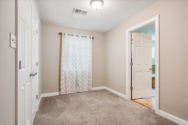 carpeted spare room featuring a textured ceiling