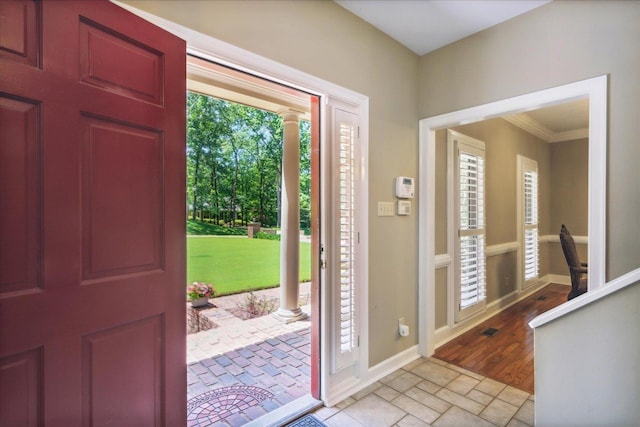 foyer with decorative columns, plenty of natural light, and crown molding