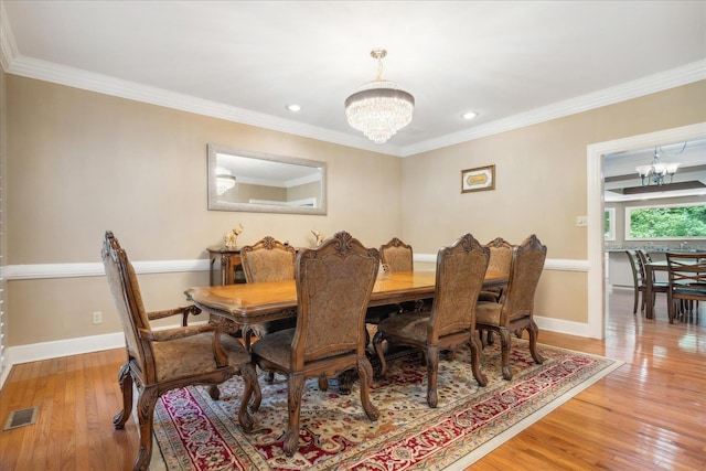 dining space with crown molding, light hardwood / wood-style flooring, and a chandelier