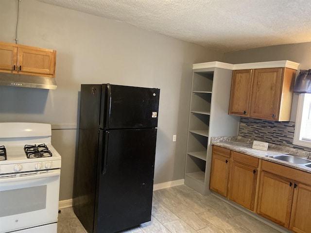 kitchen with black fridge, sink, decorative backsplash, a textured ceiling, and white range with gas stovetop