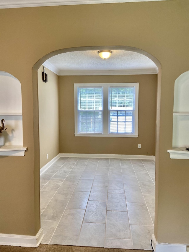 tiled empty room with a textured ceiling and ornamental molding