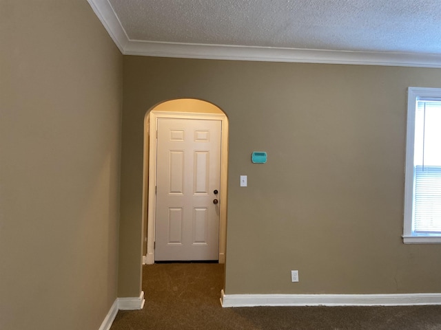 empty room featuring dark colored carpet, a textured ceiling, and ornamental molding