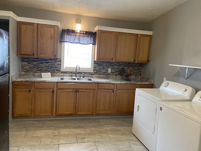 clothes washing area with washer and clothes dryer, cabinets, sink, and a textured ceiling