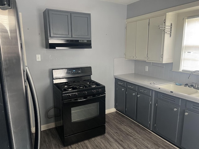 kitchen featuring black range with gas cooktop, tasteful backsplash, dark wood-style floors, under cabinet range hood, and a sink