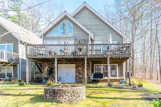 back of property featuring a yard, a fire pit, and a wooden deck