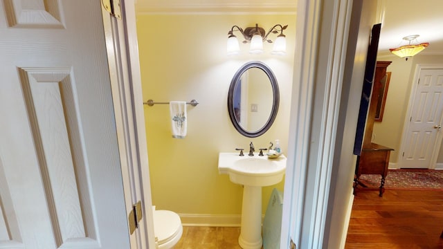 bathroom featuring hardwood / wood-style flooring, toilet, and ornamental molding