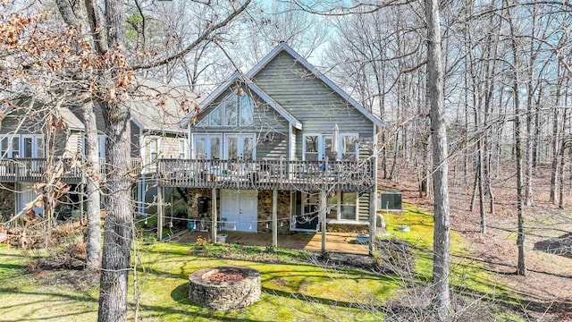 back of house with a deck, a lawn, and a fire pit