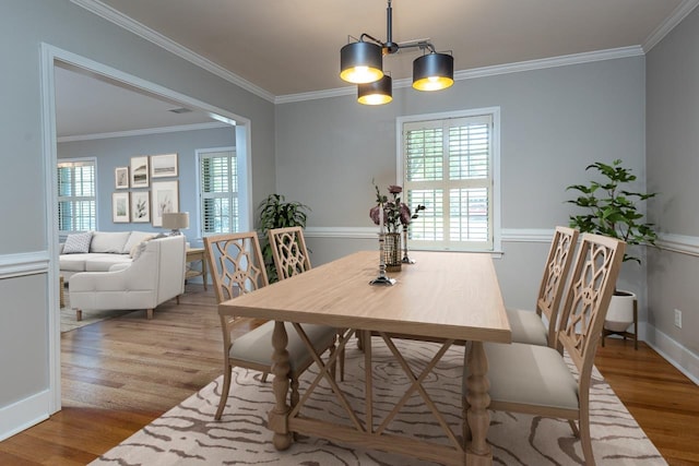 dining area featuring crown molding, a chandelier, and light hardwood / wood-style floors