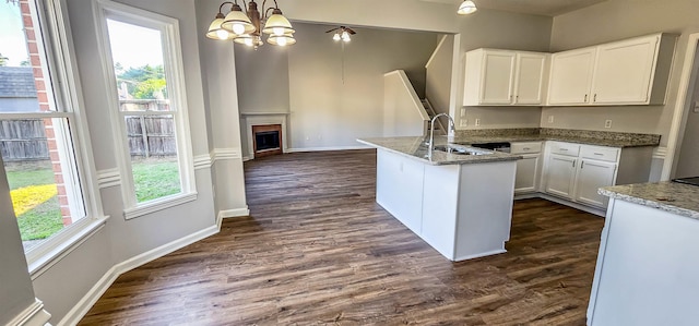 kitchen with light stone counters, sink, white cabinets, and decorative light fixtures