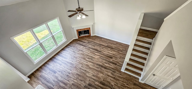 unfurnished living room featuring dark hardwood / wood-style flooring, a towering ceiling, and a healthy amount of sunlight