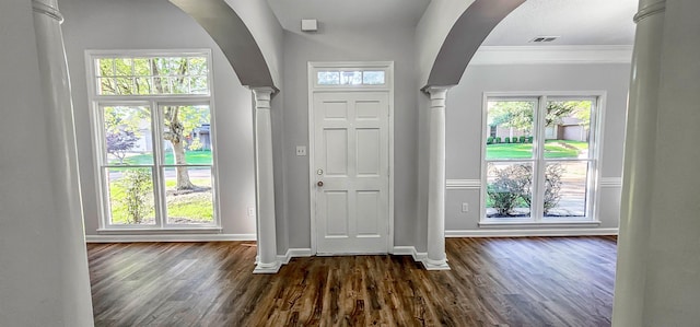 foyer featuring dark hardwood / wood-style floors, ornamental molding, and decorative columns