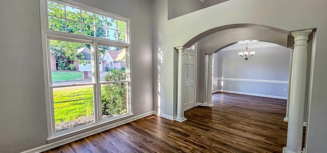 interior space with decorative columns, dark hardwood / wood-style flooring, a high ceiling, and a notable chandelier