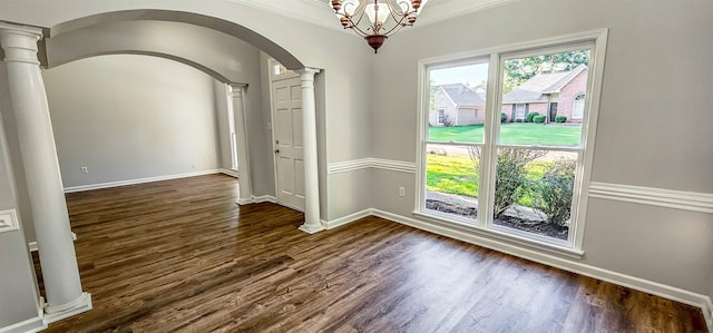 unfurnished room featuring decorative columns, crown molding, and an inviting chandelier