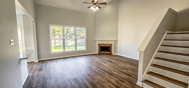 unfurnished living room with high vaulted ceiling, ceiling fan, and dark wood-type flooring