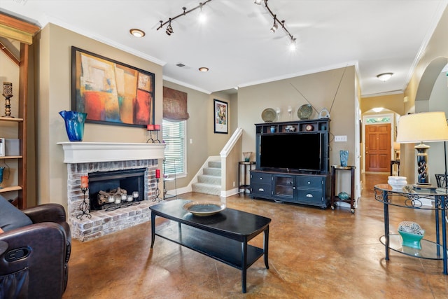 living room with a brick fireplace, concrete floors, crown molding, and track lighting