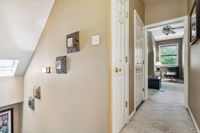 hall featuring light colored carpet and lofted ceiling with skylight