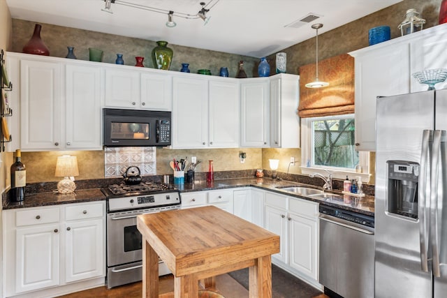 kitchen with sink, white cabinets, decorative light fixtures, and appliances with stainless steel finishes