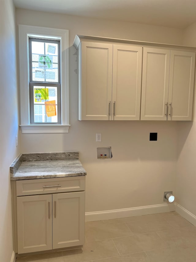 laundry room with a healthy amount of sunlight, light tile patterned floors, cabinets, and washer hookup