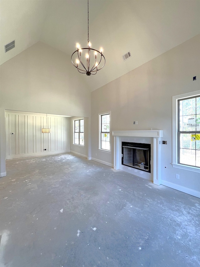 unfurnished living room with a notable chandelier, a wealth of natural light, and high vaulted ceiling