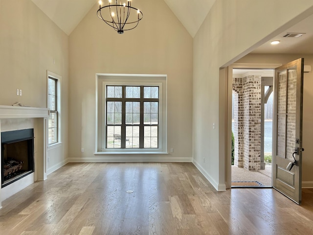 entryway featuring high vaulted ceiling, a notable chandelier, and light wood-type flooring