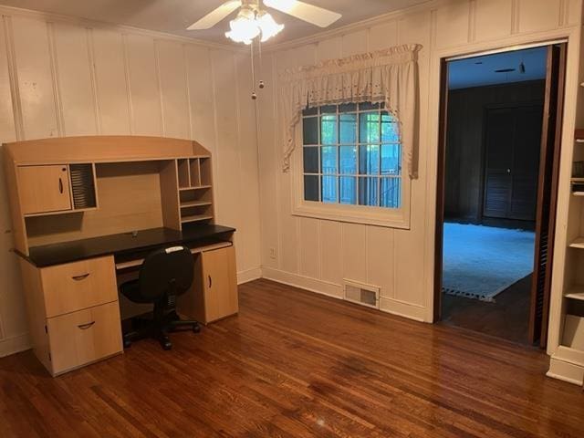 unfurnished office with built in desk, dark hardwood / wood-style floors, and ceiling fan