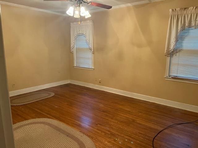 empty room with ceiling fan, dark hardwood / wood-style flooring, and crown molding