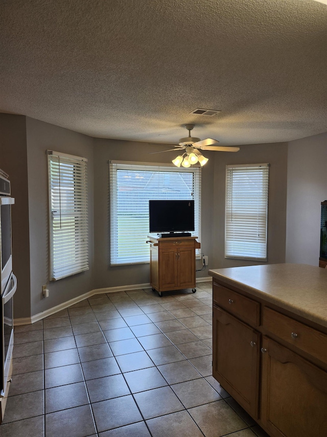 kitchen with ceiling fan, light tile patterned flooring, and a textured ceiling