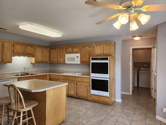 kitchen with washer and clothes dryer, white appliances, sink, ceiling fan, and light tile patterned floors