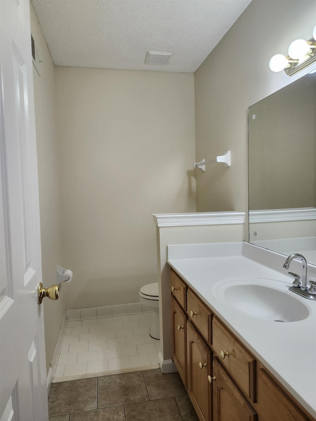 bathroom with tile patterned flooring, vanity, a textured ceiling, and toilet