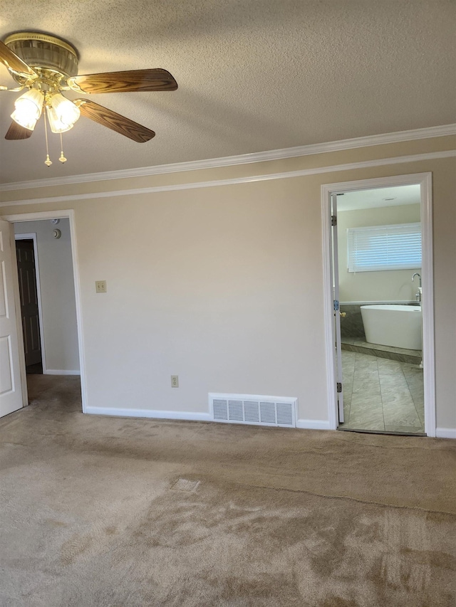 carpeted spare room with ceiling fan, a textured ceiling, and ornamental molding