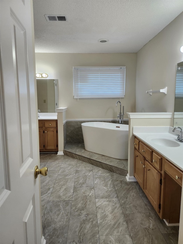 bathroom featuring vanity, a bath, and a textured ceiling