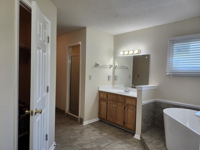 bathroom with plus walk in shower, vanity, and a textured ceiling