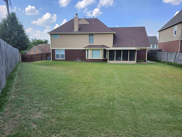 back of property with a yard and a sunroom