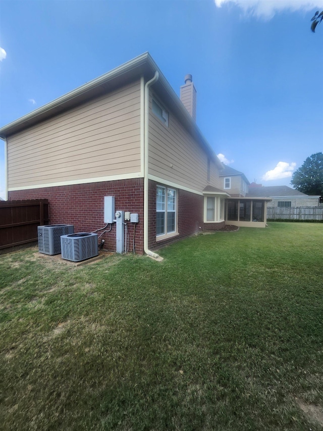 back of property featuring a yard, cooling unit, and a sunroom