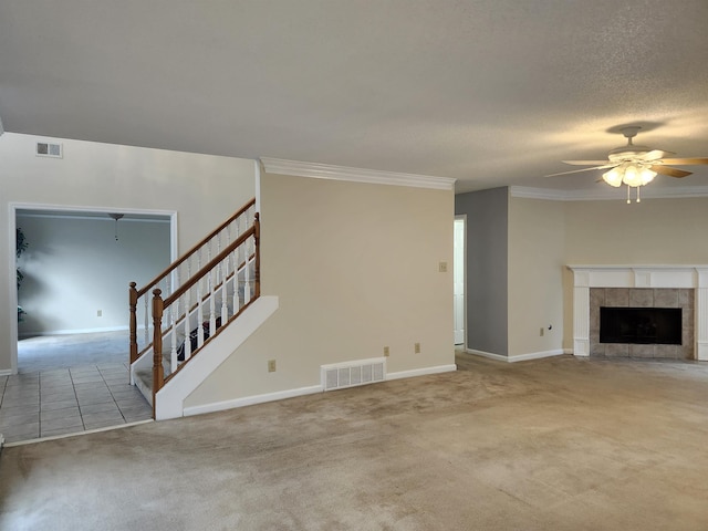 unfurnished living room featuring ceiling fan, carpet floors, crown molding, and a tile fireplace