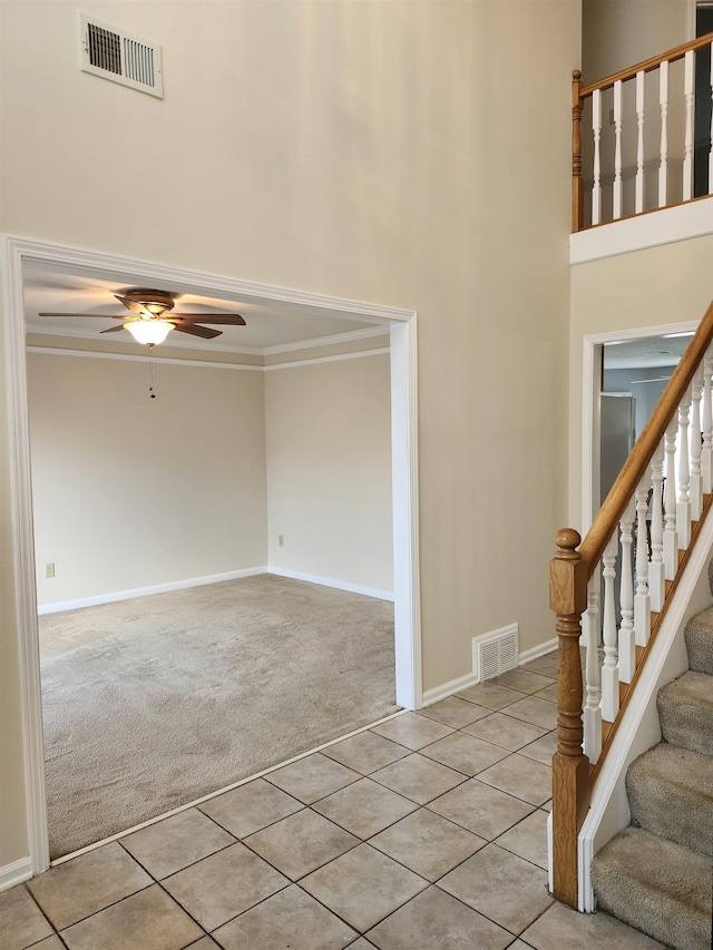 foyer entrance with light carpet, ceiling fan, and ornamental molding