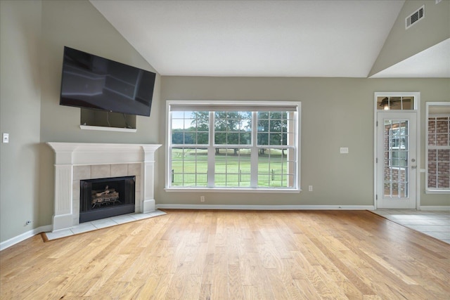 unfurnished living room featuring lofted ceiling, a fireplace, and light hardwood / wood-style flooring