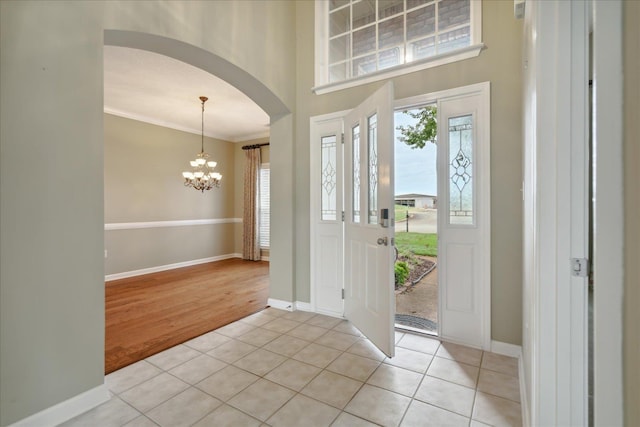 tiled entryway featuring a chandelier and ornamental molding