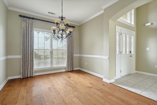 unfurnished dining area with light hardwood / wood-style floors, crown molding, and a chandelier