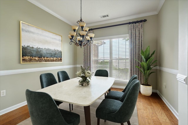 dining room with a notable chandelier, light hardwood / wood-style floors, and crown molding