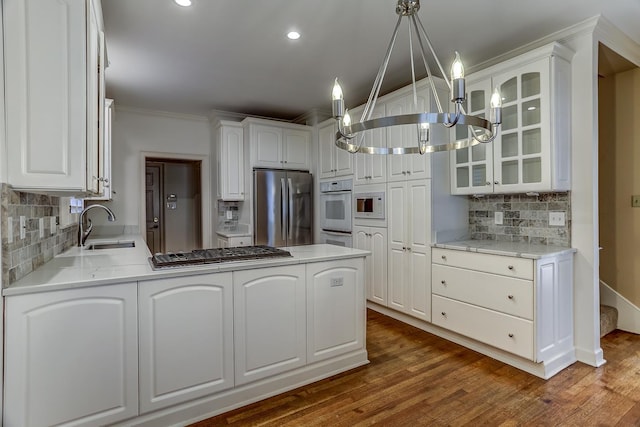 kitchen with white cabinets, tasteful backsplash, decorative light fixtures, kitchen peninsula, and stainless steel appliances