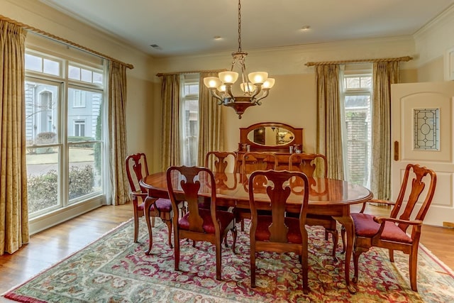 dining space with ornamental molding, light wood-type flooring, and a notable chandelier