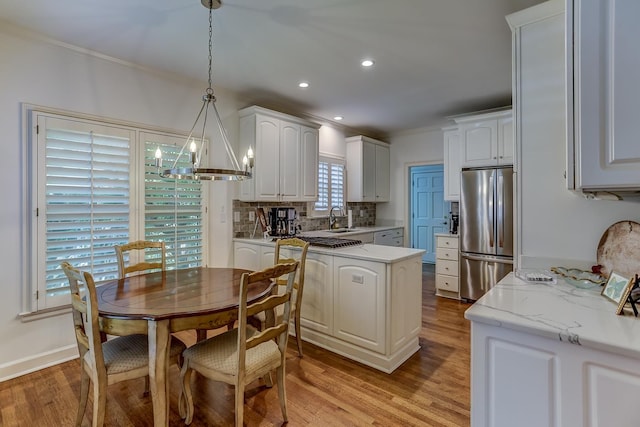 kitchen featuring light hardwood / wood-style floors, white cabinetry, hanging light fixtures, and appliances with stainless steel finishes