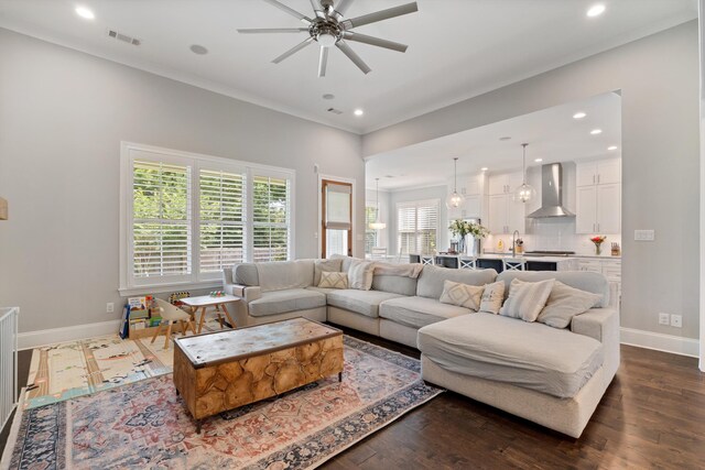 living room featuring dark hardwood / wood-style flooring, ceiling fan, crown molding, and sink