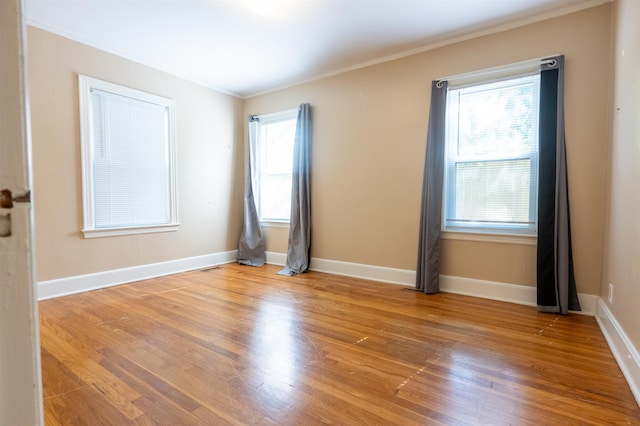 spare room with light wood-type flooring and crown molding