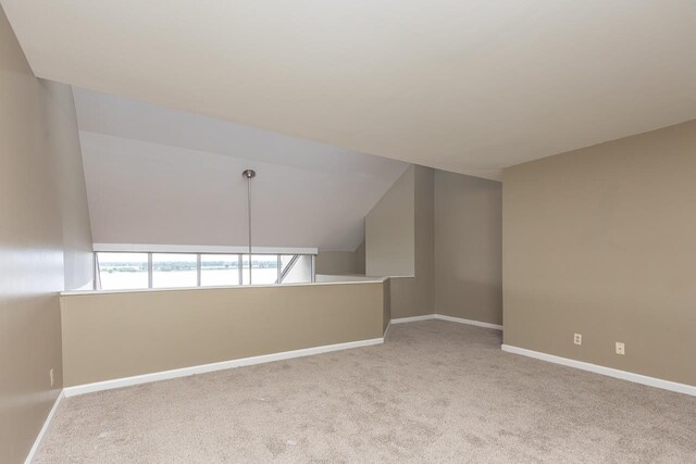 carpeted empty room with lofted ceiling