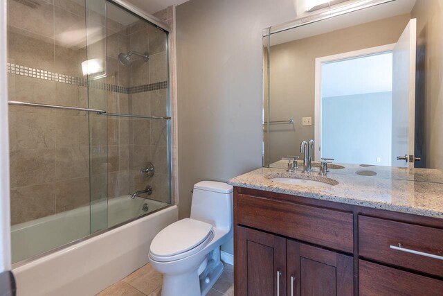 full bathroom with tile patterned flooring, bath / shower combo with glass door, vanity, and toilet