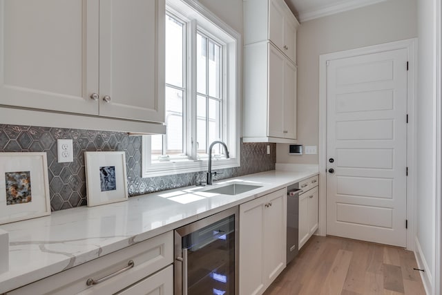 kitchen featuring white cabinetry, light stone countertops, sink, beverage cooler, and backsplash