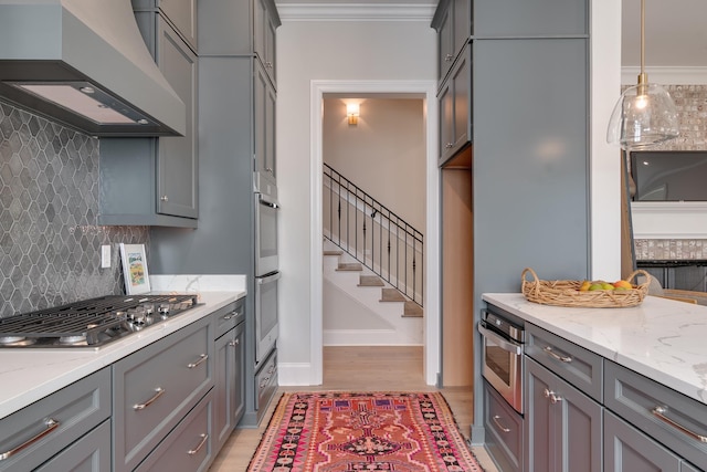 kitchen with appliances with stainless steel finishes, pendant lighting, gray cabinetry, and custom exhaust hood