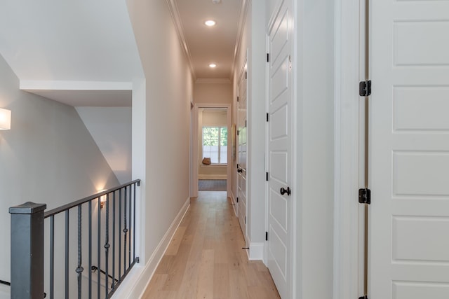 corridor with light wood-type flooring and crown molding